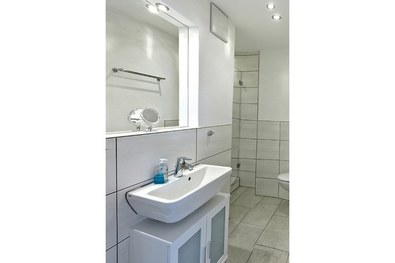 Schönes Badezimmer mit Spiegel, Waschbecken, WC und Dusche.