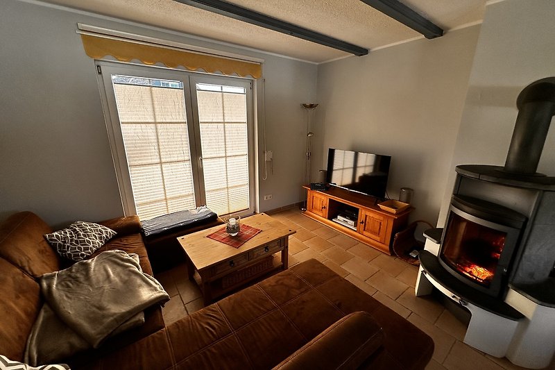 Wohnzimmer mit gemütlicher Couch, Tisch, TV und Kamin.