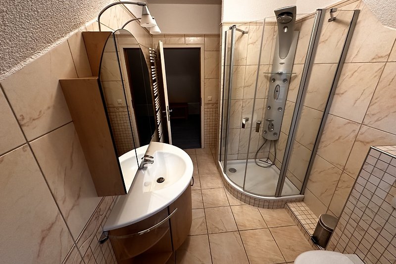 Badezimmer mit moderner Dusche, Waschbecken und Spiegel.
