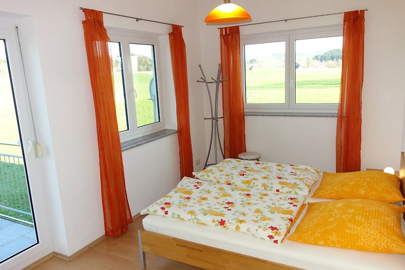 Gemütliches Schlafzimmer mit Holzbett und gelben Textilien.