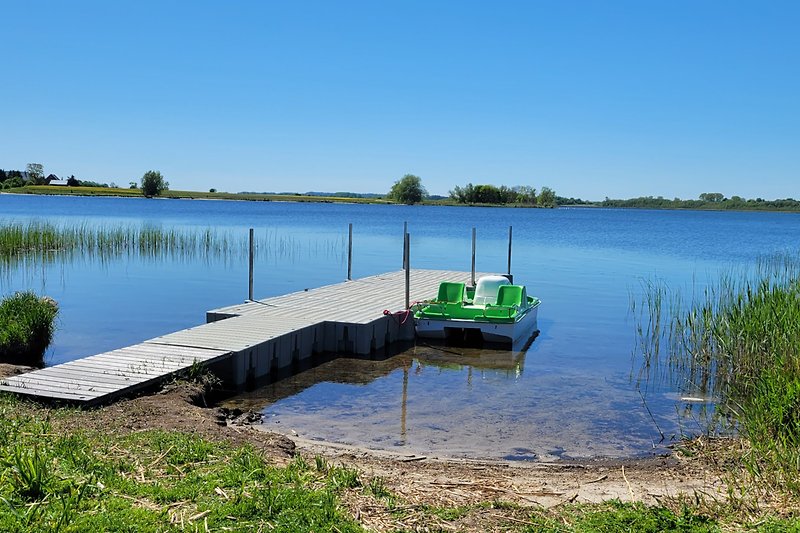 Ruhiger See mit Boot, umgeben von üppiger Natur und Bäumen.