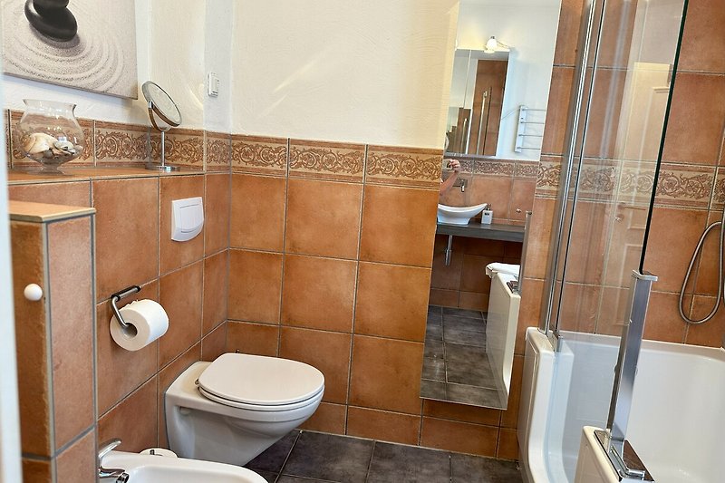 Gemütliches Badezimmer mit WC, Bidet und zusätzlichem Spiegelschrank
