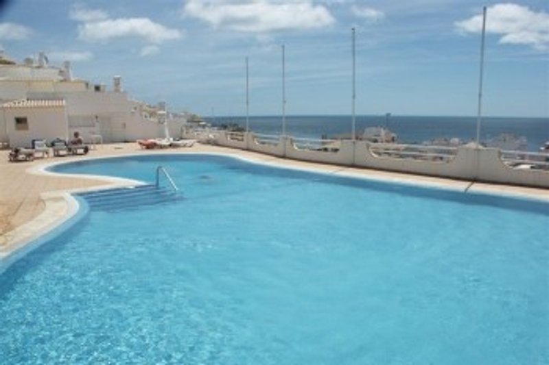 Zwembad met zonneterras; op de achtergrond de zee.