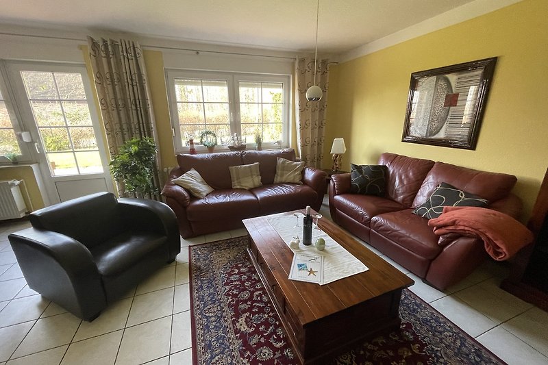 Wohnzimmer mit brauner Couch, Pflanze, Tisch und Fenster.
