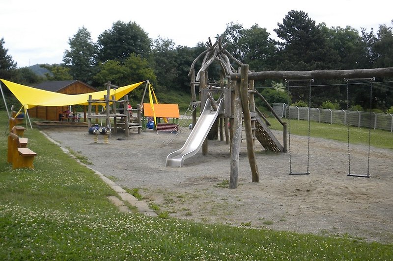 Schöner Spielplatz mit Rutsche und Grünflächen.