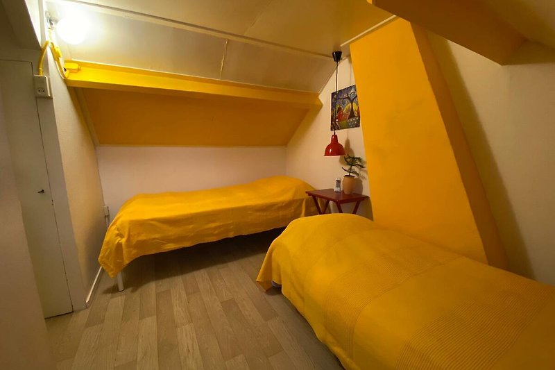 Gemütliches Schlafzimmer mit Holzbett und orangefarbenem Bettgestell.