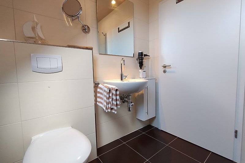 Modernes Badezimmer mit Spiegel, Badradio, Waschbecken und Armatur.