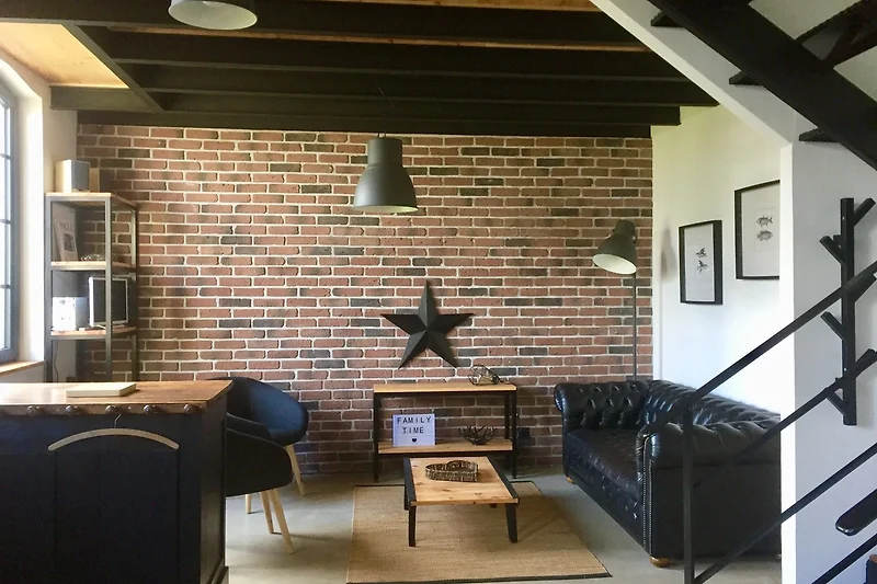 Woonkamer met een moderne inrichting, inclusief een comfortabele grijze bank, een houten koffietafel en een grote flatscreen-tv aan de muur. Het gebied is goed verlicht met natuurlijk licht dat door grote ramen komt.