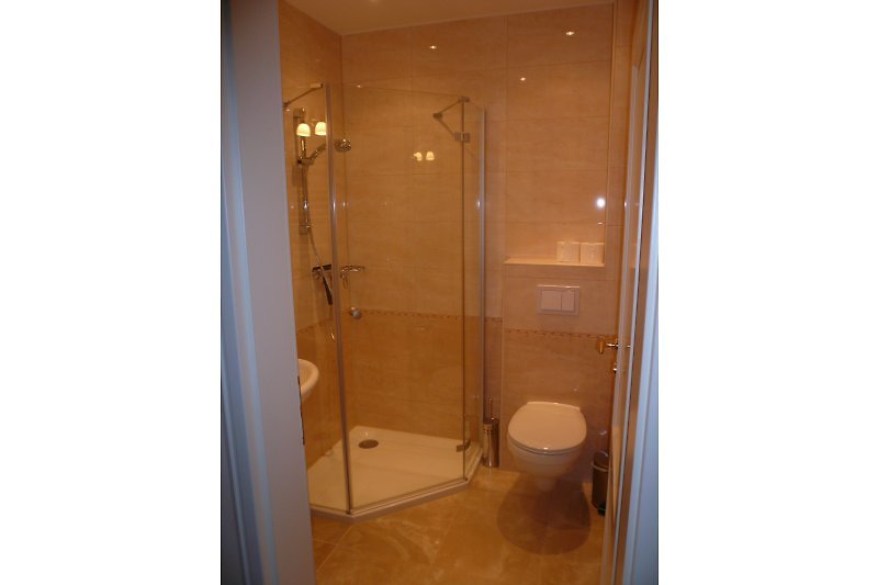 Salle de bain à l'étage d'habitation avec lavabo, douche en verre intégral, toilettes, chauffage au sol, sèche-serviettes et fenêtre extérieure (non visible)