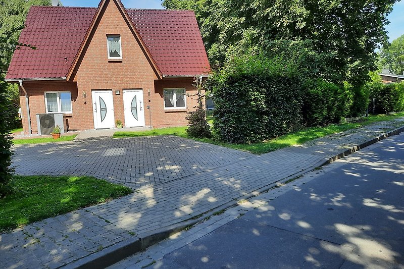 Gemütliches Landhaus mit Garten, Ziegelmauerwerk und Asphaltweg. Eingang zur Wohnung rechts